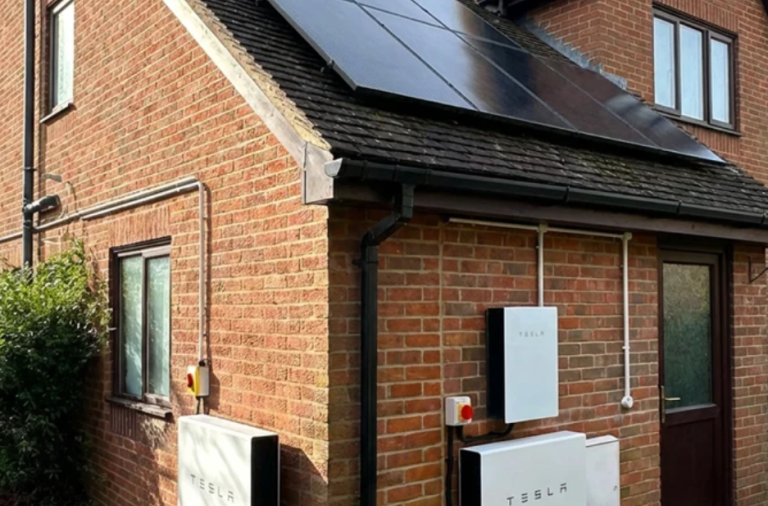 Home battery storage system installed on an exterior wall next to a residential property