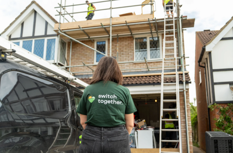 Installer fitting solar panels on a residential roof as part of a home energy upgrade