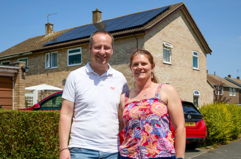 Residents standing outside a home with solar panels installed on the roof