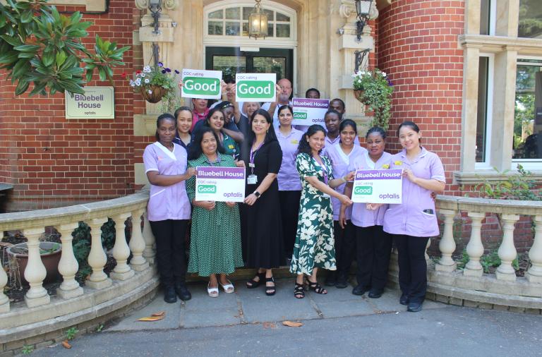 Staff from Bluebell House outside the building marking its good CQC rating with celebratory signage