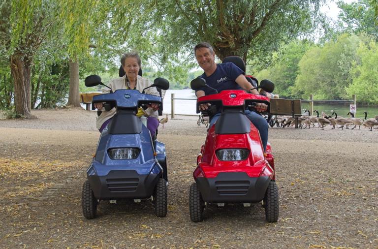 Two people using mobility scooters at Dinton Pastures Country Park.