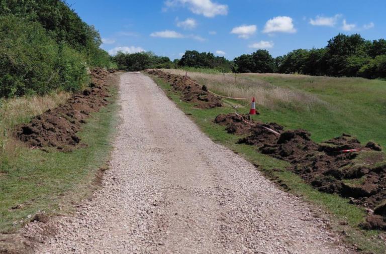 Footpath improvements underway through grassland at Ashenbury Park, with excavated soil beside the route.