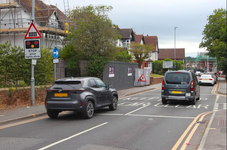 Cars driving towards the traffic lights at Wokingham station with a roadworks sign in the background