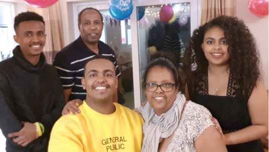 Foster carer Freweyni and her partner, two sons and daughter smile the camera at a birthday party with balloons