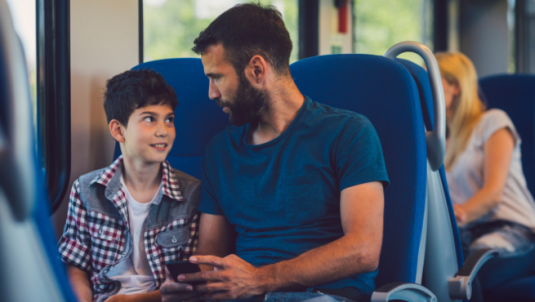 A man and his son chat while travelling on a train