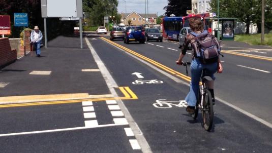 A photograph of a raised cycle track crossing in front of a side junction, with cyclists given priority over emerging traffic