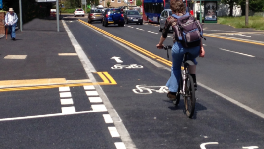 A photograph of a raised cycle track crossing in front of a side junction, with cyclists given priority over emerging traffic