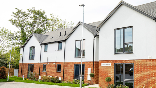 A row of properties with small grass area and parking spaces out the front