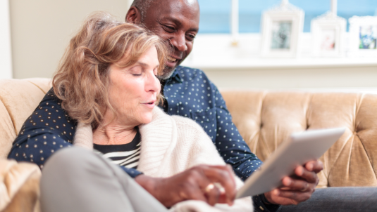 Older couple relaxing on a sofa looking at an iPad