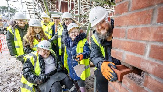 Cllr Stephen Conway, leader of the Council, joins a family as they lay a brick for their specially designed bespoke new home at Gorse Ride 