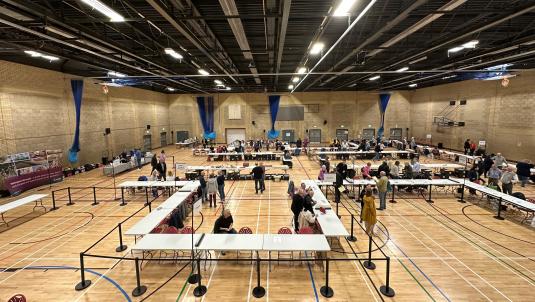 people counting ballot papers around tables