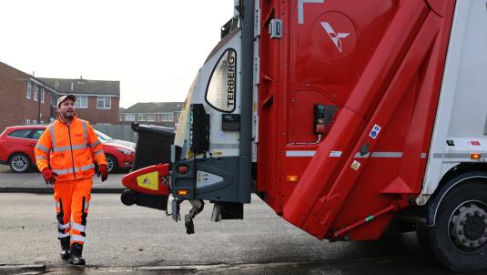 Biffa employee loading a wheeled bin onto a lorry 