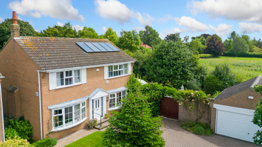 Detached house with solar panels surrounded by countryside