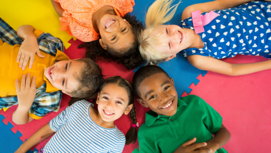 Children laying on a play mat, facing upwards