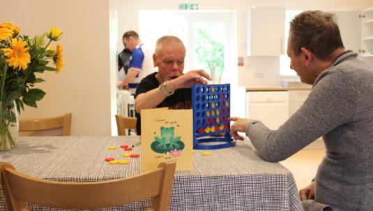 Three people playing games and cooking in their kitchen/dining room