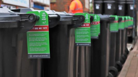 A row of wheelie bins with information tags on them