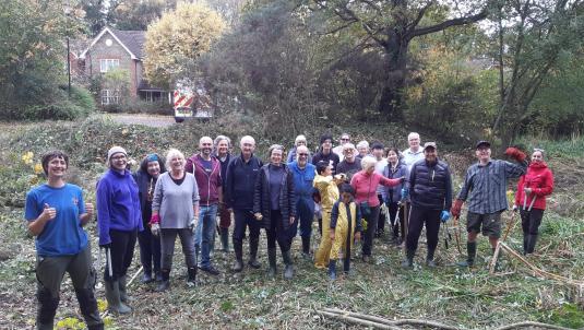 A large volunteer group standing on cleared woodland, posing together after conservation work.