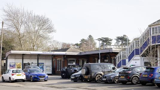 The main entrance to Twyford station on a sunny day, with lots of cars parked in front