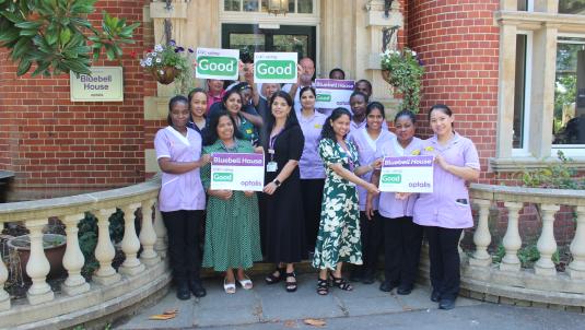 Staff from Bluebell House outside the building marking its good CQC rating with celebratory signage