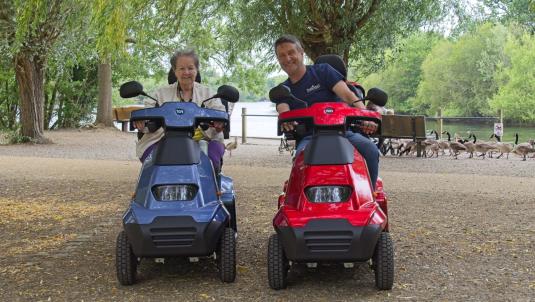 Two people using mobility scooters at Dinton Pastures Country Park.