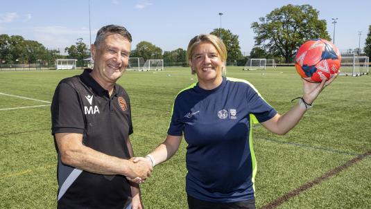 Mark Ashwell and Liz Verrall shaking hands on the 3G football pitch at Cantley Park