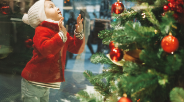 A child leaning against and looking at a Christmas shop window