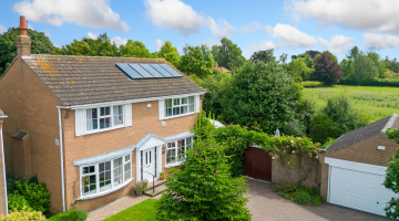 Detached house with solar panels surrounded by countryside
