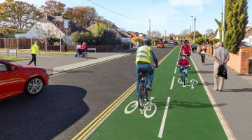 artist's impression of a cyclist riding down a new cycleway along Woodlands Avenue in Woodley, which is separate from both the road and the pavement