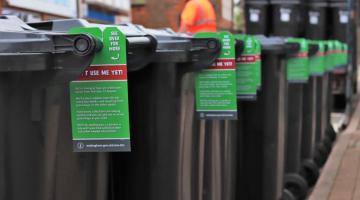 A row of wheelie bins with information tags on them