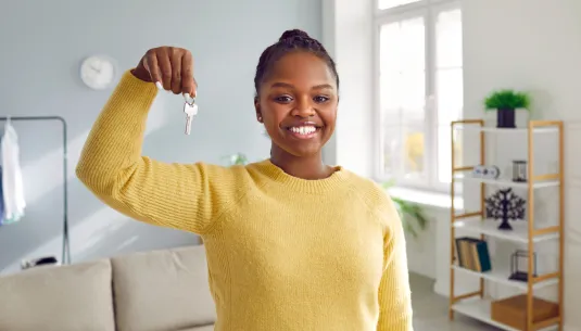 smiling girl stood in a flat holding up a bunch of house keys