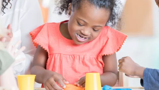 A young girl with downs syndrome playing with play dough