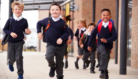 Three children in school uniform running towards the camera 