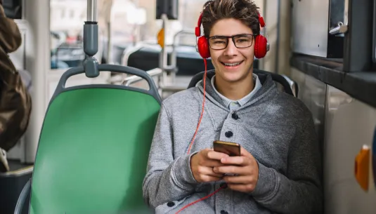 A teenage boy on the bus listening to music