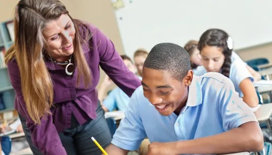 A teacher helping a secondary school pupil with a written task 