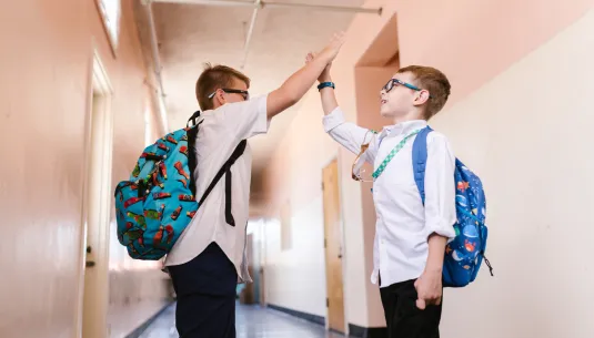 Two children in school uniform giving each other a high five