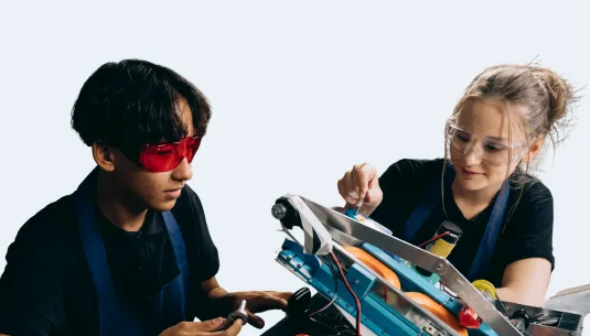Two teenagers wearing goggles and using screwdrivers to build machinery 