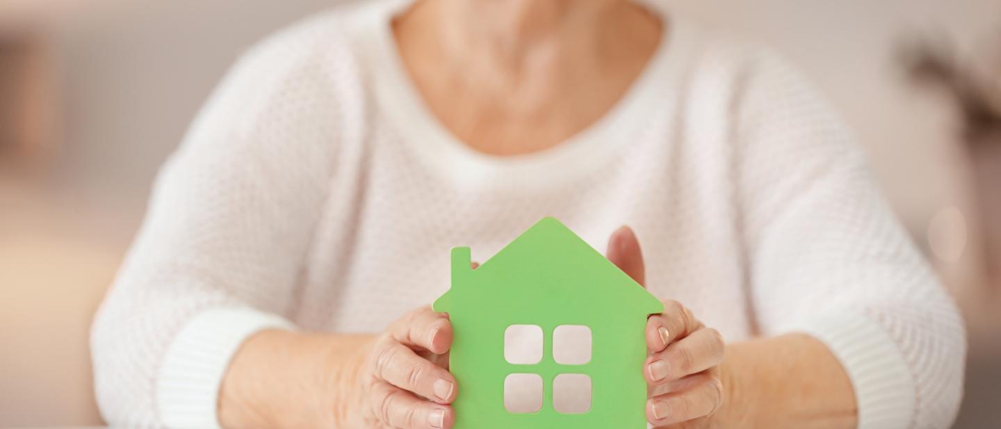 Older lady holding a cutout of a house