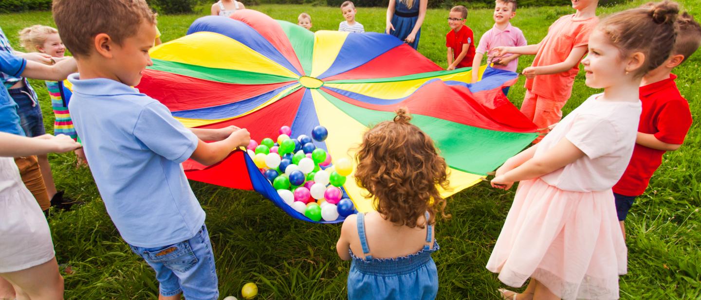 Pre school children playing a parachute game outside