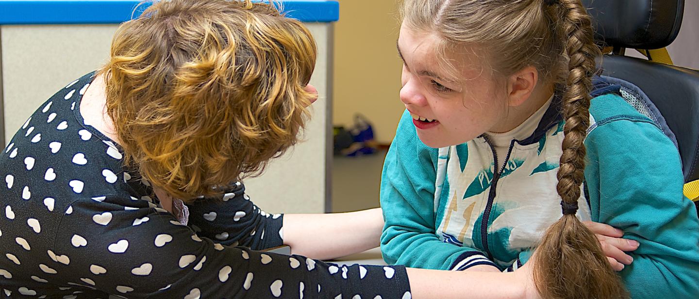 Social worker talking to teenage girl in wheelchair