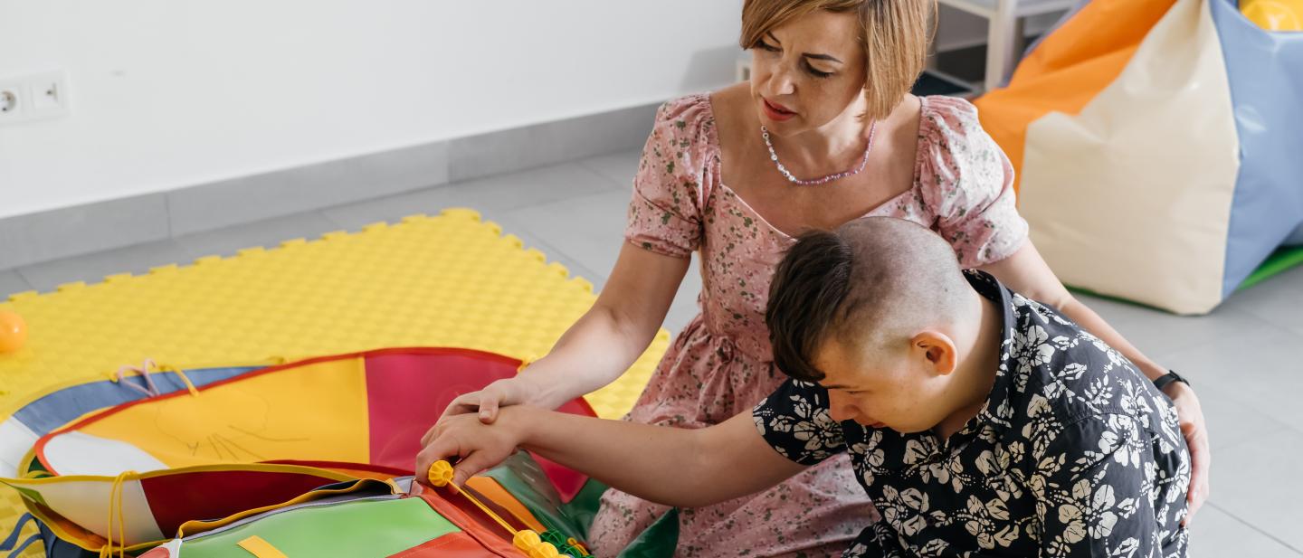 Boy playing with sensory toys as a support worker sits with him