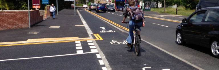 A photograph of a raised cycle track crossing in front of a side junction, with cyclists given priority over emerging traffic