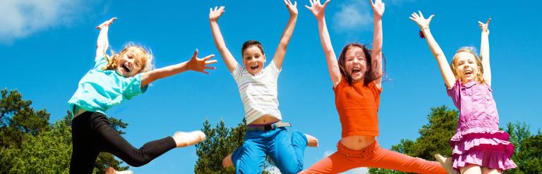 Children jumping in the air outside in a field