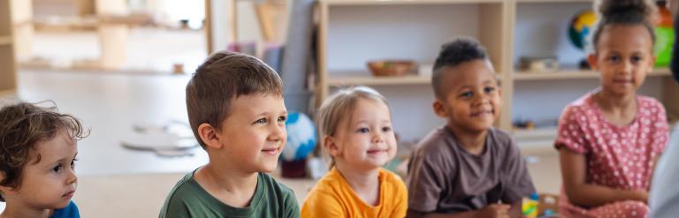 Pre-school children sat on the floor listening to their teacher