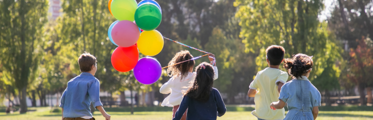 Children running with one holding a bunch of balloons